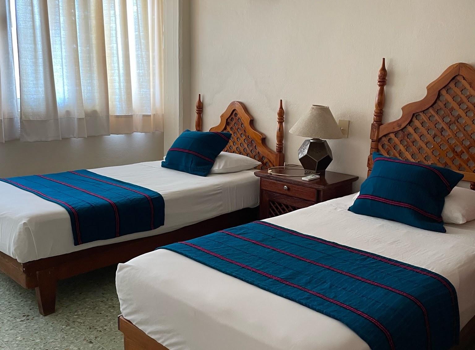 Bedroom with two beds, wooden headboards and blue Mexican blankets